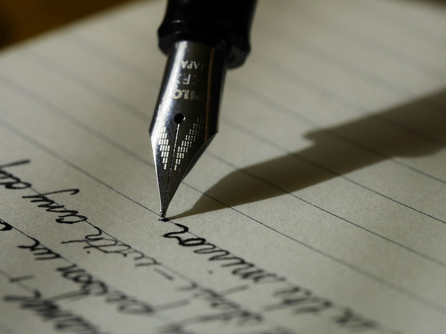 Open notebook on a wooden desk with handwritten notes and a pen